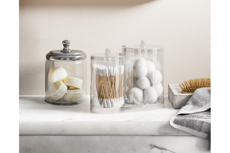 clear bathroom storage jars with cotton pads and ear buds on a tray