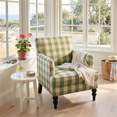 Fauteuil contemporain Lofties en polyester avec structure en bois de bouleau massif, coussins moelleux, garniture cloutée et détails capitonnés en losanges.