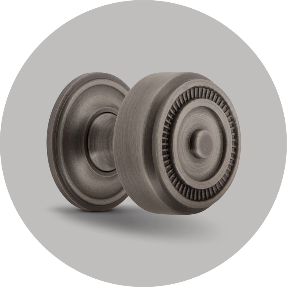 Round antique pewter door knob with a decorative fluted edge and matching circular rosette on a light gray background.