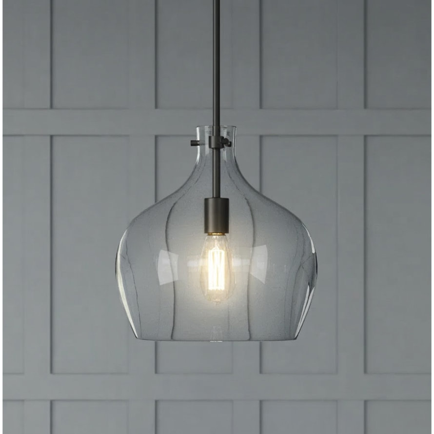Modern clear glass teardrop pendant light with a black metal downrod hanging above a dining table with blue decor and grey upholstered chairs.