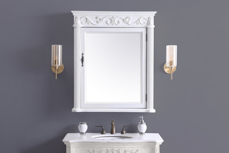 white medicine cabinet between two gold wall sconces on a dark gray bathroom wall