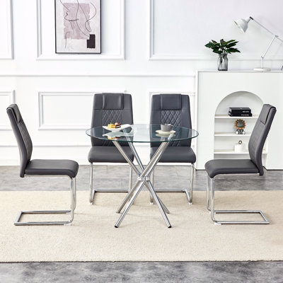 Ensemble de table et de chaises Table de salle à manger ronde en verre transparent de 36,6 po de forme unique avec des pieds en métal argenté rassemblés en forme d'anneau. Elle est accompagnée de 4 chaises de salle à manger en polyuréthane de haute
