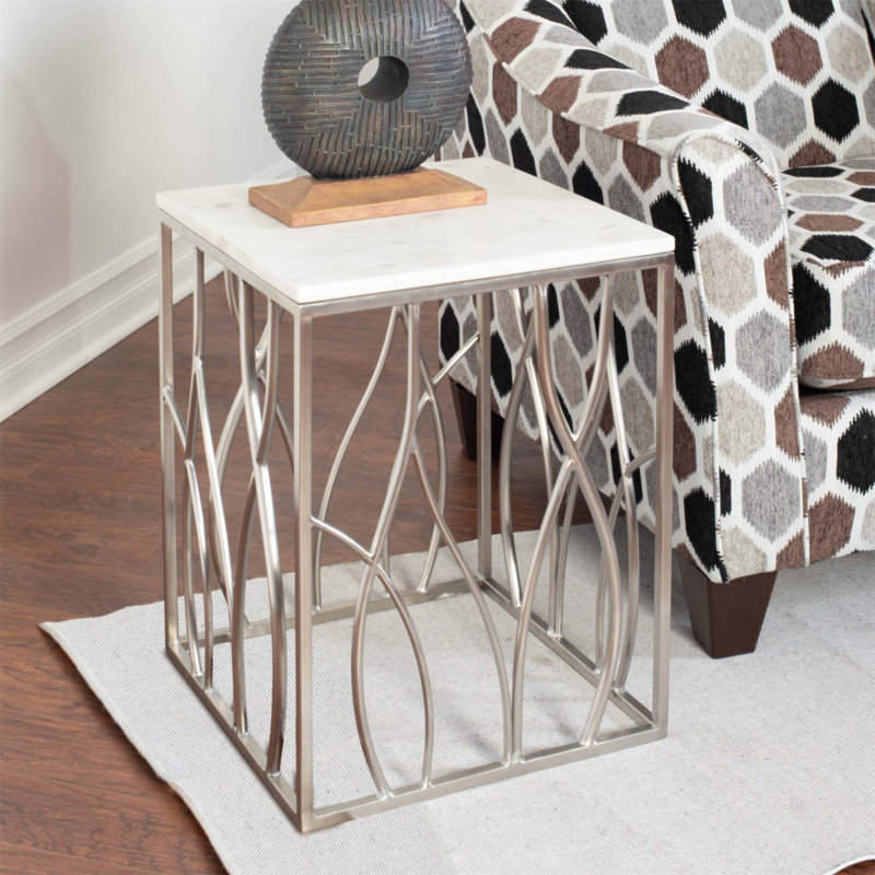 Table de bout carrée en marbre Kameral avec base en acier inoxydable, veines minérales uniques et courbes organiques pour une élégance moderne.