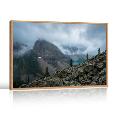 Tableau sur toile représentant un sommet de montagne brumeux surplombant un lac turquoise et une pente rocheuse