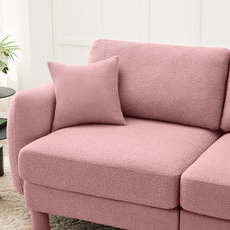 Canapé 2 places rose en tissu bouclé avec pieds cylindriques et en forme de coquillage, offrant une assise confortable et unique conçue pour un confort de détente dans la chambre.