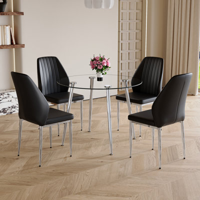Ensemble de table et de chaises.Une table de salle à manger ronde moderne de 38,6 pouces de diamètre avec plateau en verre trempé transparent et pieds en métal argenté, ensemble de 4 chaises de salle à manger confortables en polyuréthane noir avec dossier allongé.