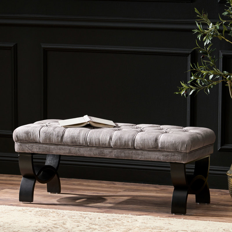 Banc moderne en velours gris avec pieds élégants et courbes pour une utilisation polyvalente dans votre maison
