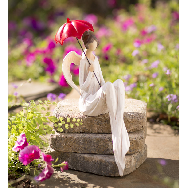 Statue d’ange assis avec un parasol rouge