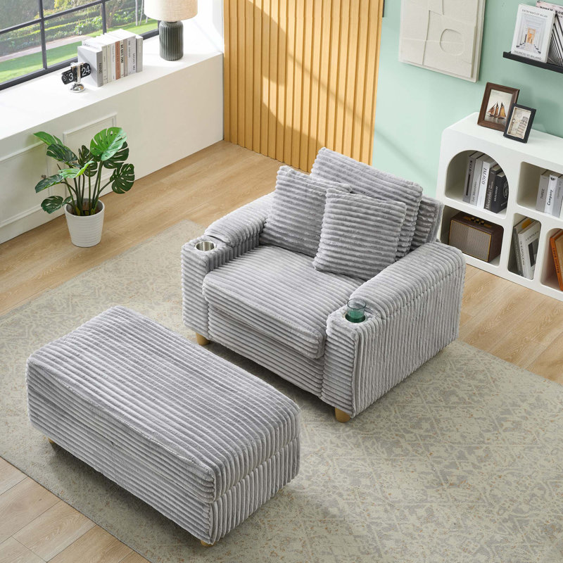 Grey corduroy single sofa with one pillow, two throw pillows, a footstool and two storage Spaces.