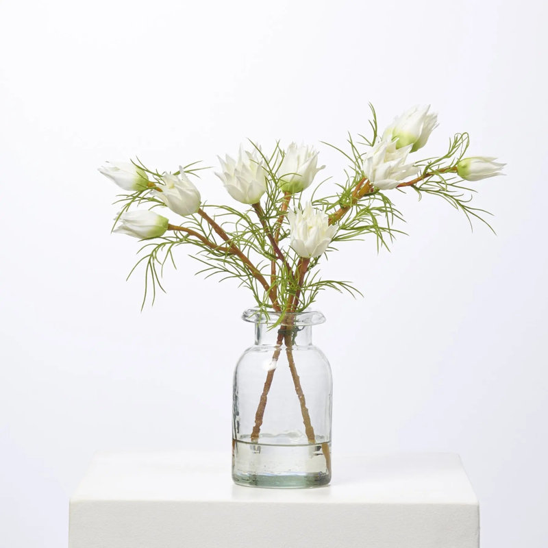 Mini arrangement de fleurs blanches dans un petit vase transparent