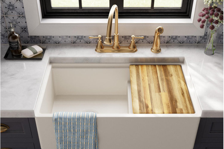 farmhouse-style kitchen sink with gold faucet and side sprayer featuring fitted wood sink cover