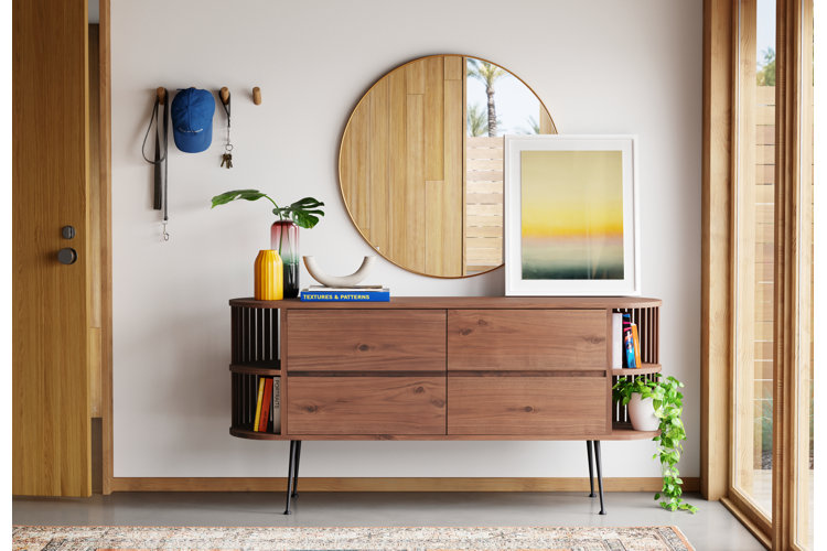 Entry way console able with a round gold framed mirror and mid century modern accents featured in guide on where to place a mirror