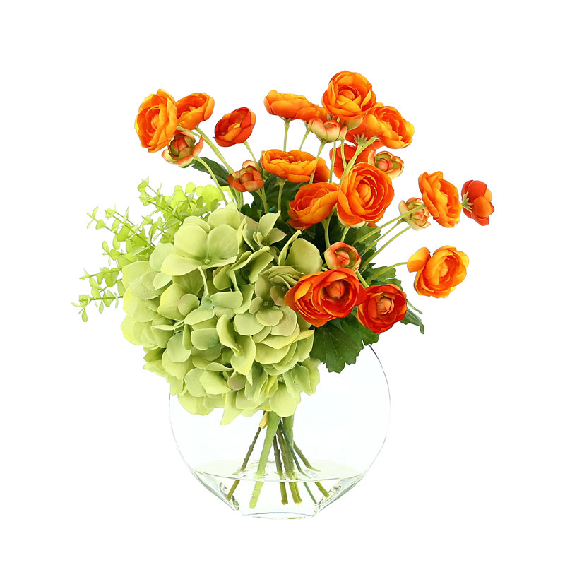 Renoncule, hortensia et eucalyptus disposés dans un vase en verre transparent