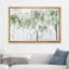 Framed canvas wall art featuring an abstract watercolor forest scene in pastel green and white in a light wood frame.