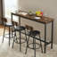 Ensemble de table de bar et de chaises pour 3, ensemble de table de salle à manger industriel 4 pièces avec 3 tabourets de bar rembourrés en polyuréthane, ensemble de table de bar pour la cuisine, la salle à manger, le salon, le bar, le café, le coin petit espace, brun rustique