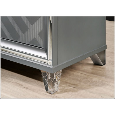 Commode de style contemporain avec des pieds en acrylique, des faux tiroirs en losange art déco et des poignées argentées pour une élégance moderne