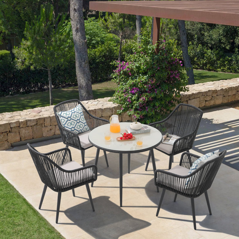 Ahriella 4 - Person Patio Dining Set with Round Table , Cushions Included, Black Frame/Light Gray Cushion