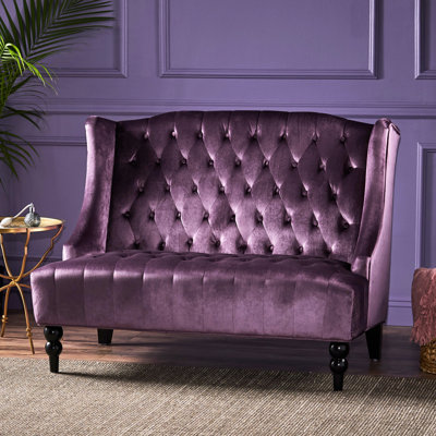 Fauteuil à oreilles sophistiqué en velours couleur raisin, orné d'un magnifique capitonnage à boutons. Dimensions : 130 cm (L) x 84,4 cm (P) x 96,4 cm (H). Détails des boutons : 130 cm (L) x 96,4 cm (H) x 84,4 cm (P).