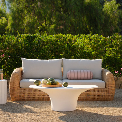 Outdoor wicker sofa with plush white cushions paired with a round white coffee table