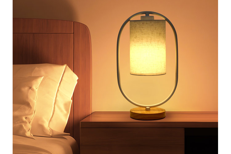 yellow lantern table lamp on a nightstand next to a bed with a wood headboard