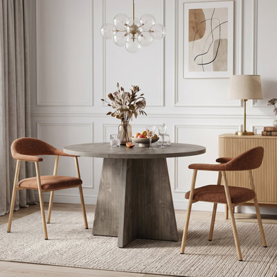 Ensemble de salle à manger comprenant une table ronde sur pied central, des chaises rembourrées et capitonnées, et des meubles de salle à manger.