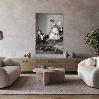 1950S 1960S Teen Couple In Living Room In Prom Dress & Tuxedo Guy Sitting On Floor & Girl Dancing To Music From A Record Player Romantic Contempora...