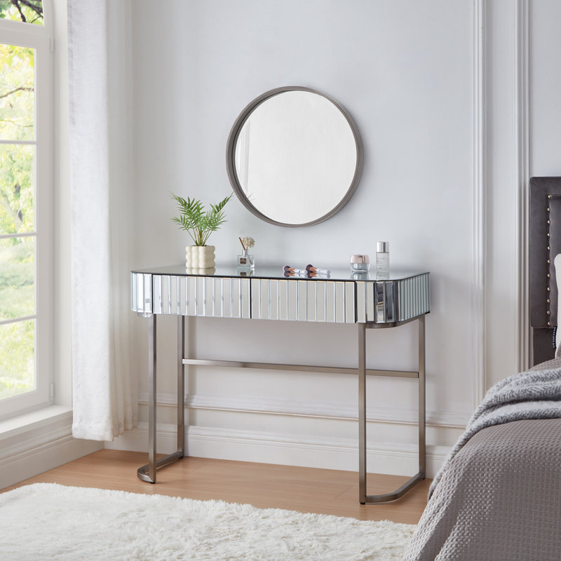 Élégante coiffeuse en acier inoxydable et miroir avec beaucoup de rangement, des bords doux et une utilisation polyvalente pour un décor moderne.