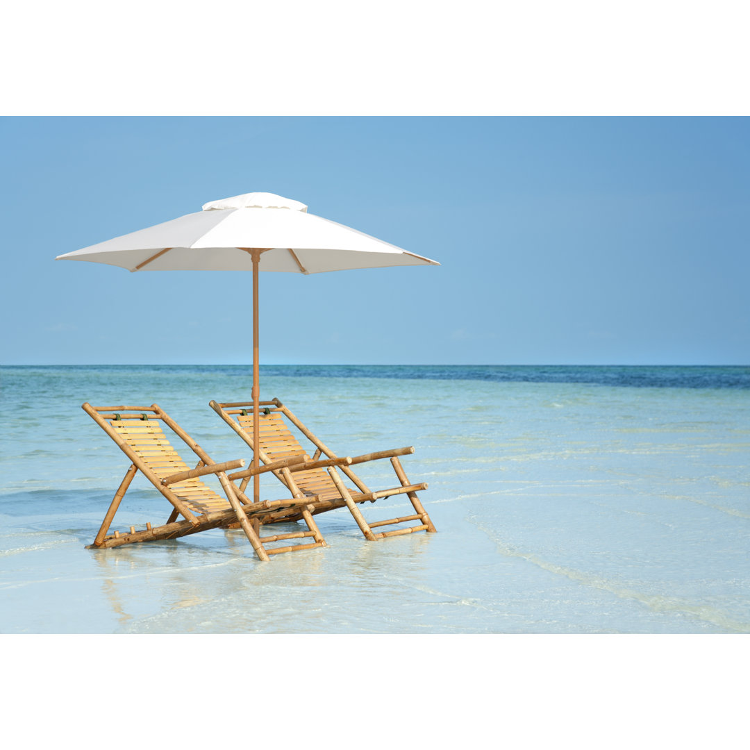 Bambusstühle und Sonnenschirm an einem Strand in Florida, USA