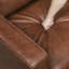 Sofa rustique deux places en similicuir au chocolat, avec accoudoirs droits et passepoil décoratif.