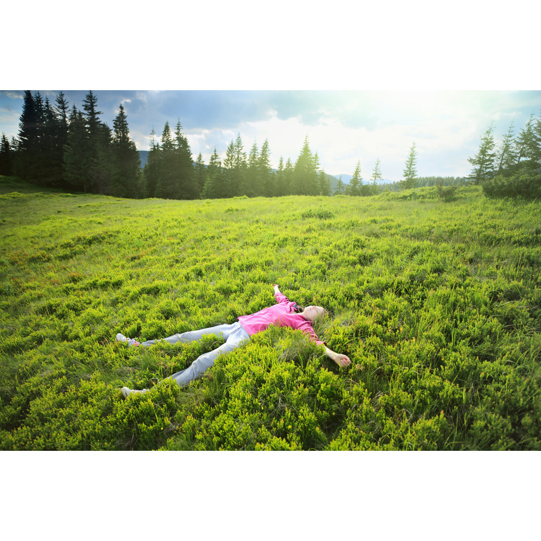 Frau liegt im Gras