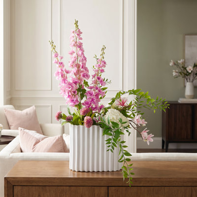 Composition de delphiniums et d'hortensias dans un vase en céramique cannelée