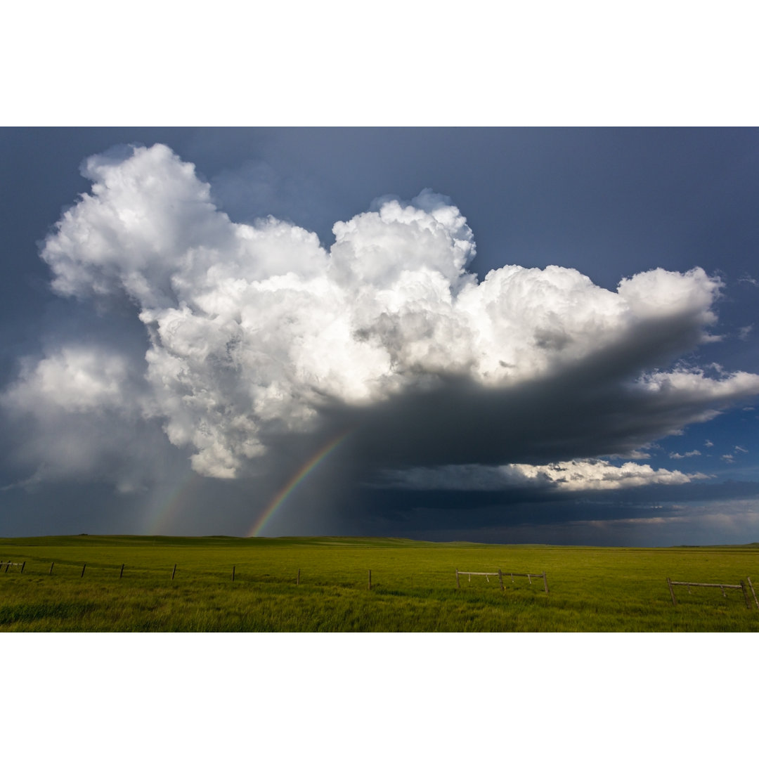 Gewitterwolke mit Silberstreifen und doppeltem Regenbogen über grünem Feld in Montana