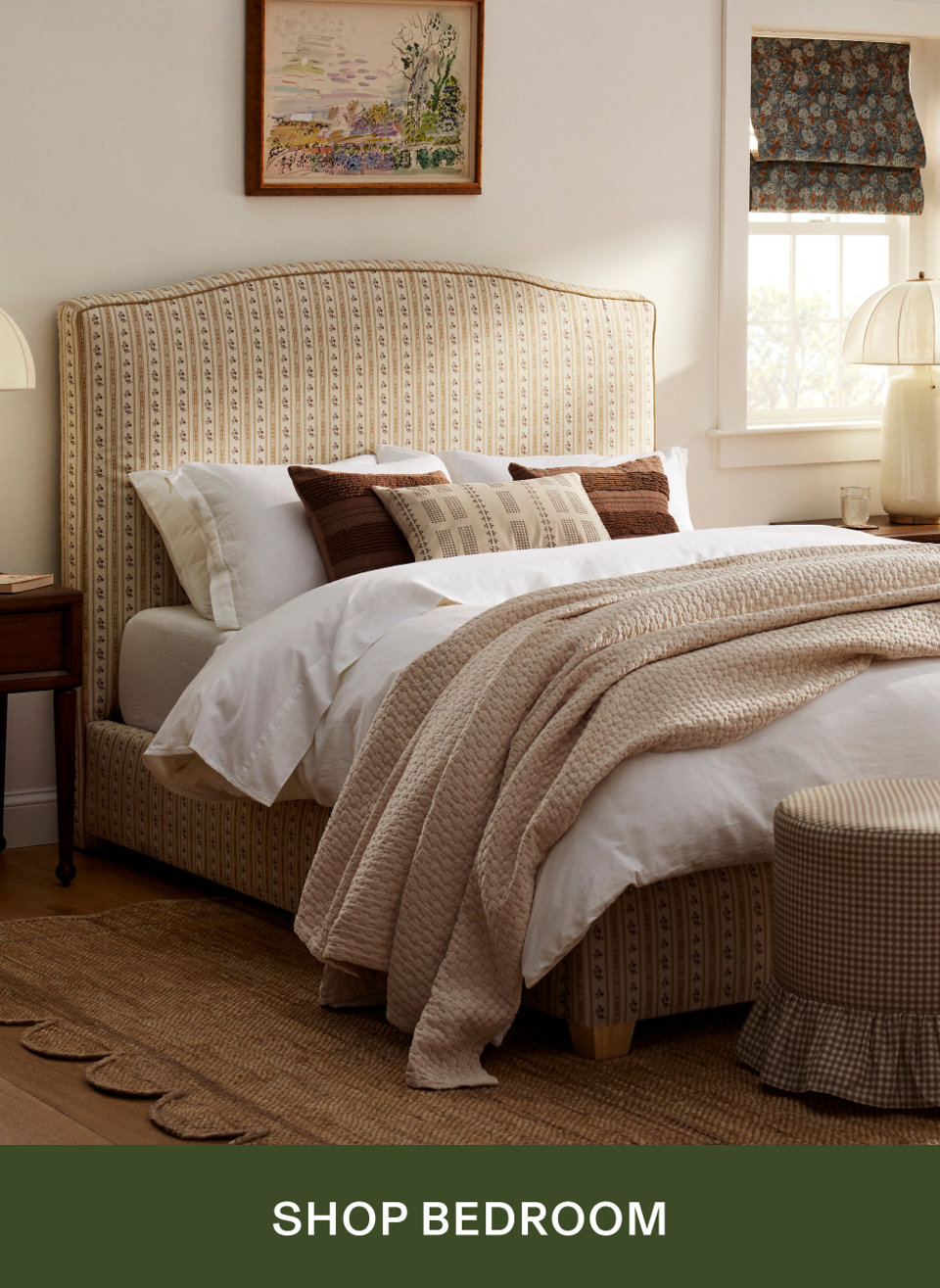Upholstered bed with a striped pattern, white bedding, and decorative pillows in a cozy, neutral bedroom, with the text SHOP BEDROOM.
