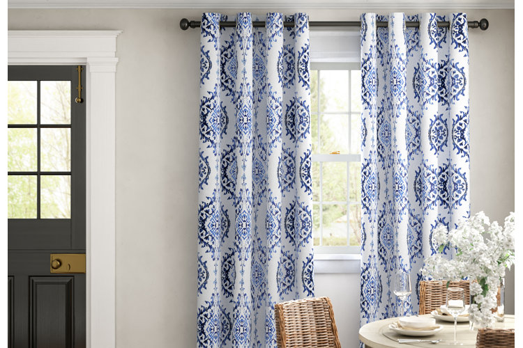 coastal dining room with wicker dining chairs in front of blue damask curtains