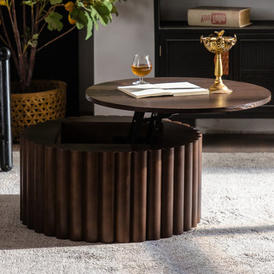 Table basse ronde relevable artisanale, structure robuste, rangement dissimulé, profondeur de 70 cm, idéale pour se détendre à la maison. Plateau orné de motifs en relief.
