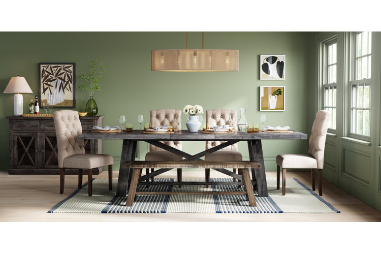 Dining room with green walls with rustic dining room table and white floral centerpiece and large rattan ceiling light