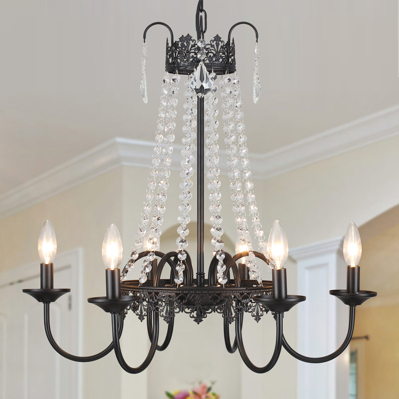 Close-up of a black chandelier with crystal strands and six candle-style lights, shown against a softly lit neutral-toned ceiling.