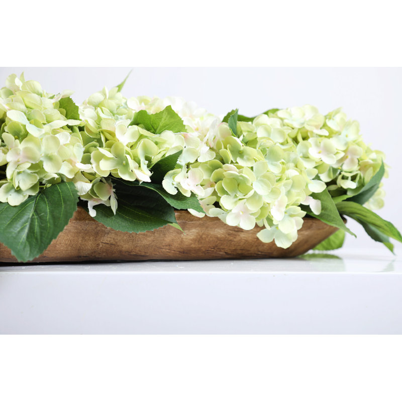Mélange d'hortensias crème et vert avec centre de table à profil bas dans un bol à pain en bois