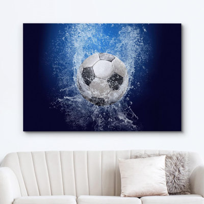 Canvas wall art featuring a soccer ball splashing into blue water, displayed above a white sofa.