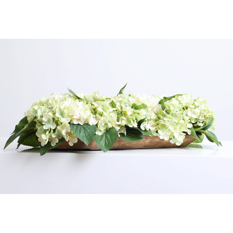 Mélange d'hortensias crème et vert avec centre de table à profil bas dans un bol à pain en bois
