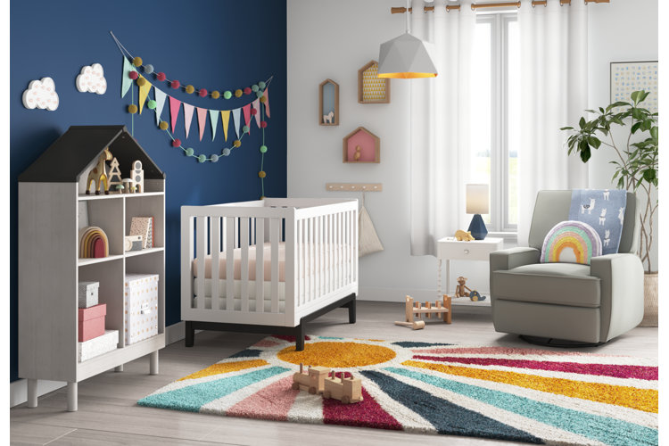 nursery with multicolor sunbeam rug, a white crib, and a gray accent chair