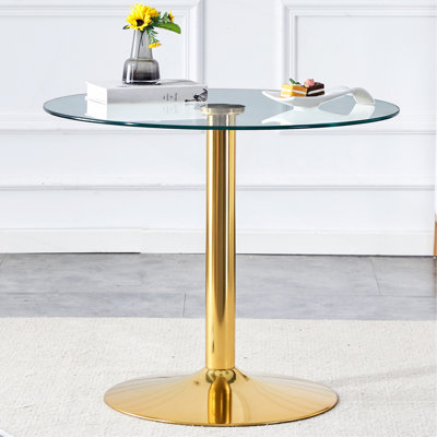 Un plateau en verre de 35 pouces de diamètre et une table de salle à manger ronde moderne et minimaliste avec des pieds en métal doré. Idéal pour les salles à manger, les salons et les salles de réunion.