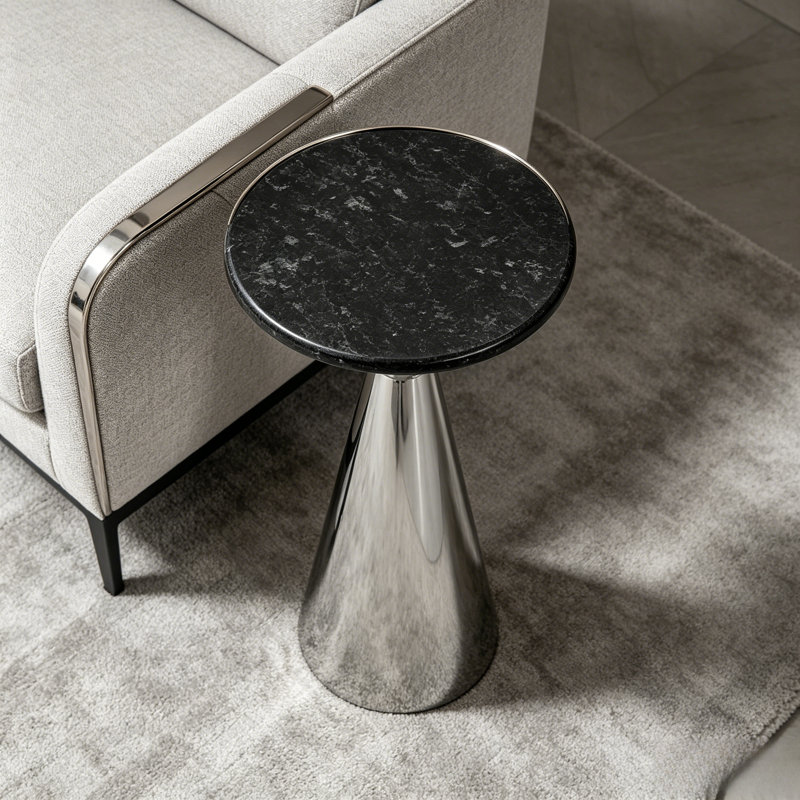 Table d'appoint haute sur pied, plateau d'aspect marbre noir et piètement conique en métal chromé poli, table basse moderne et mince pour salon et chambre.