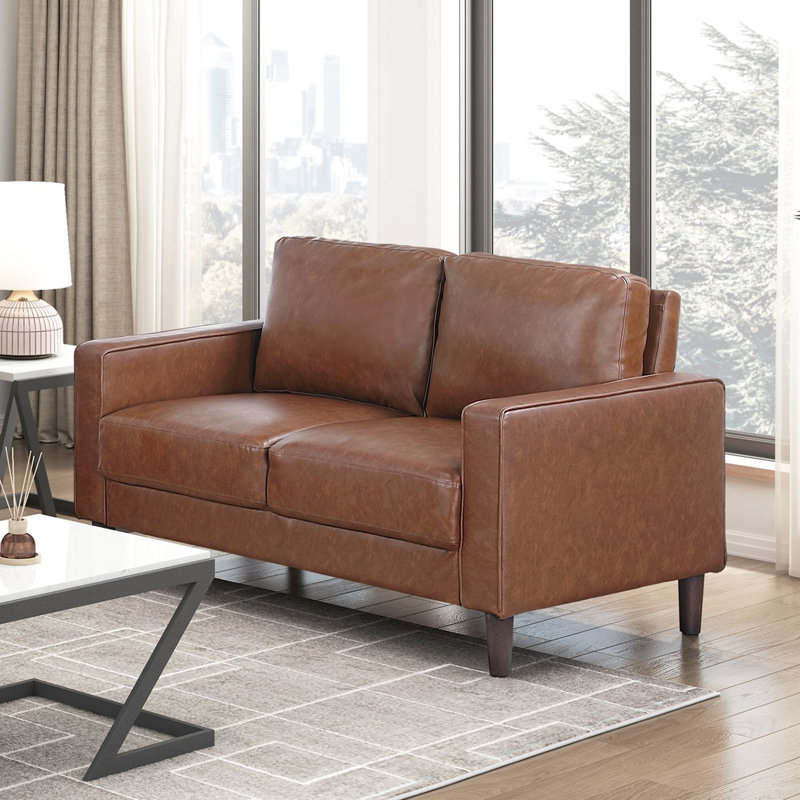 Sofa rustique deux places en similicuir au chocolat, avec accoudoirs droits et passepoil décoratif.