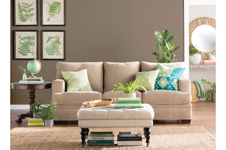 neutral couch and rug with green accent pillows and wall art