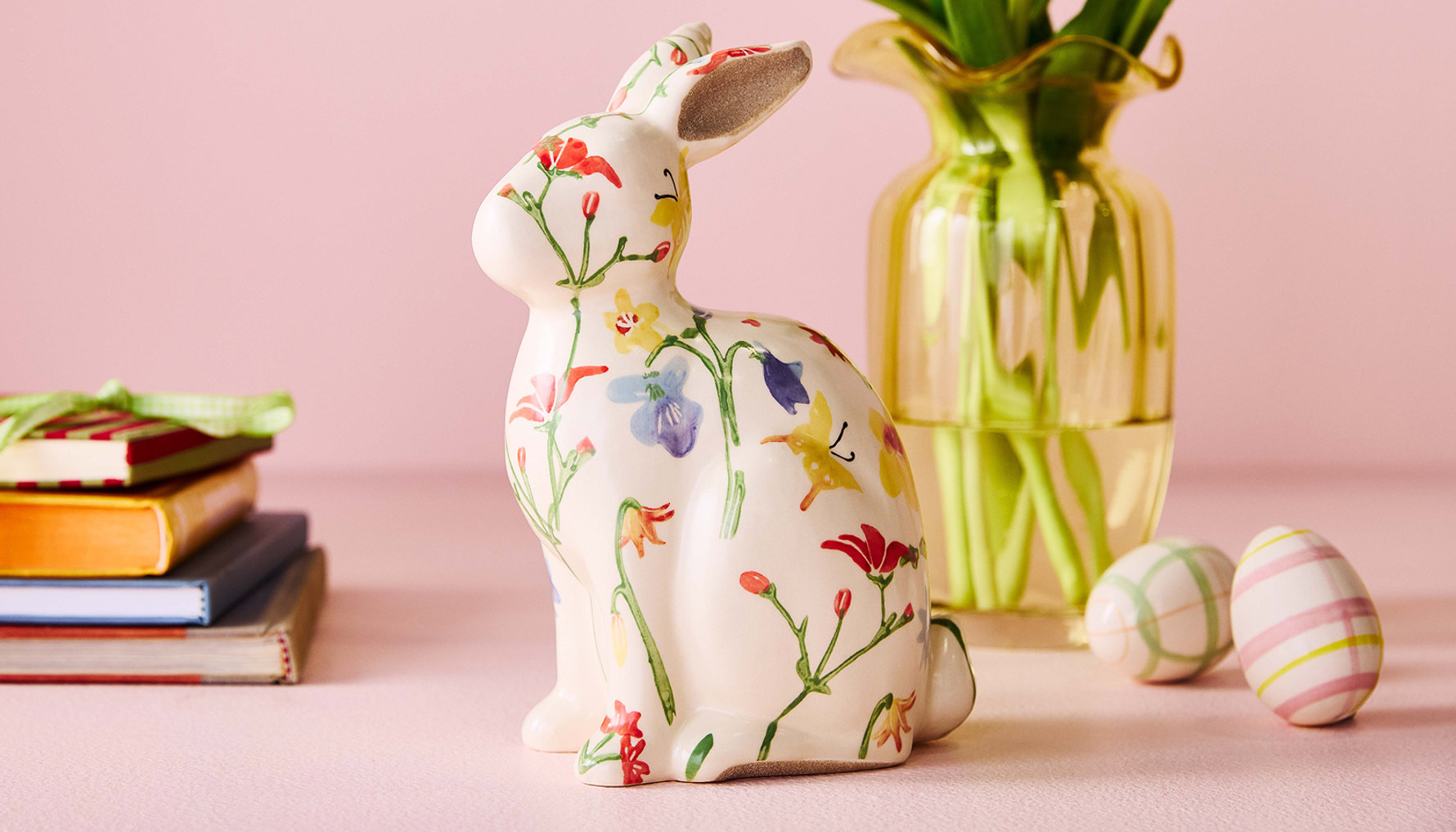 Figurine de lapin floral avec livres, vase et œufs de Pâques.