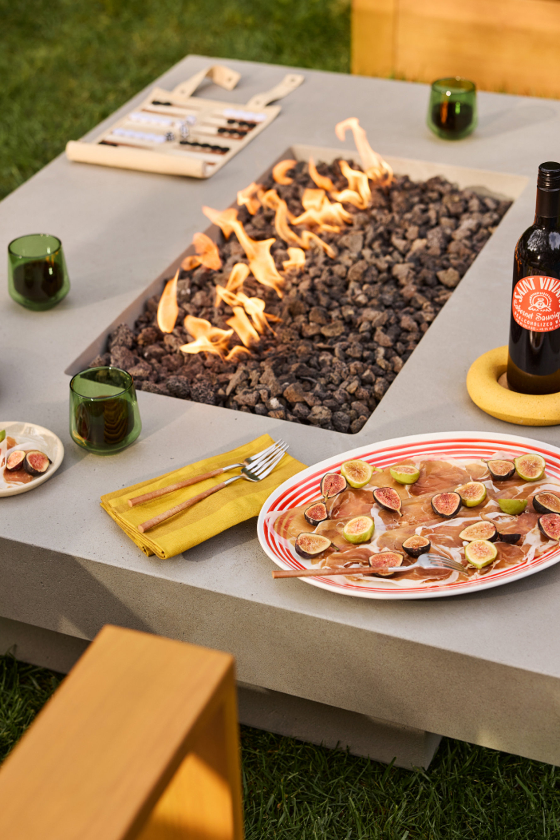 Grey fire pit table with wine and appetizer plates.