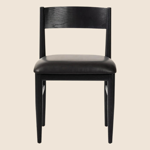 Black dining chair with a curved wooden backrest and a cushioned leather seat on a light background.