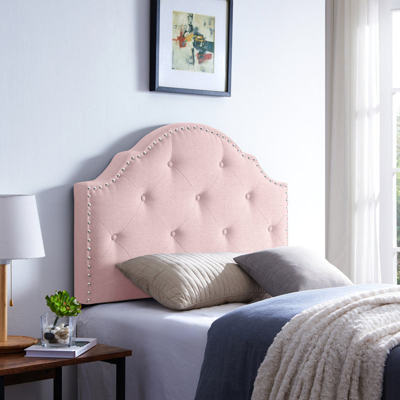 Tête de lit simple en tissu rosé avec coutures captivantes et garniture cloutée élégante aux accents contemporains
