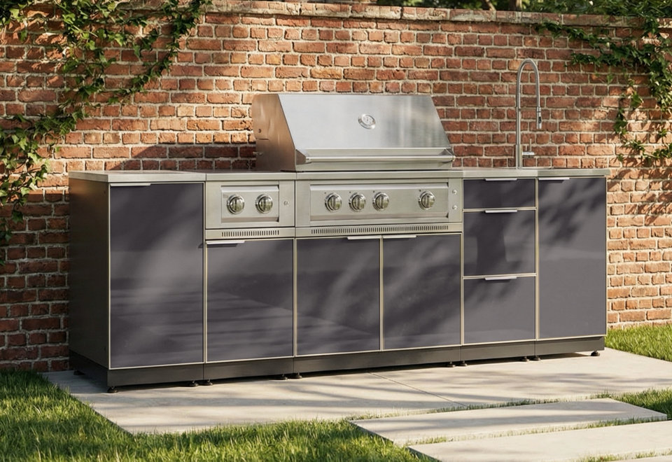 Stainless steel outdoor kitchen island with a built-in grill and sink set against a brick wall.